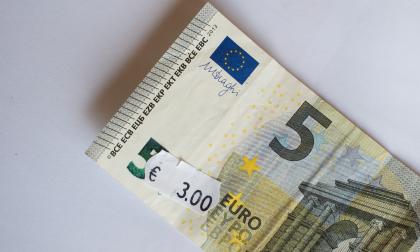 Five euro banknote with three euro price tag. Selective focus on label.