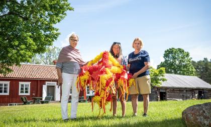 Marthorna Anna-Lisa Johansson, Lina Antman och Ann Carlsson visar upp en av kronorna som ska pryda midsommarstången på Jan Karlsgården.
