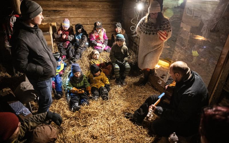 Prästen Stefan Äng till höger berättar och sjunger om stallkatten Kalles upplevelser i stallet. Barnen från församlingens tisdagsklubb lyssnar uppmärksamt.